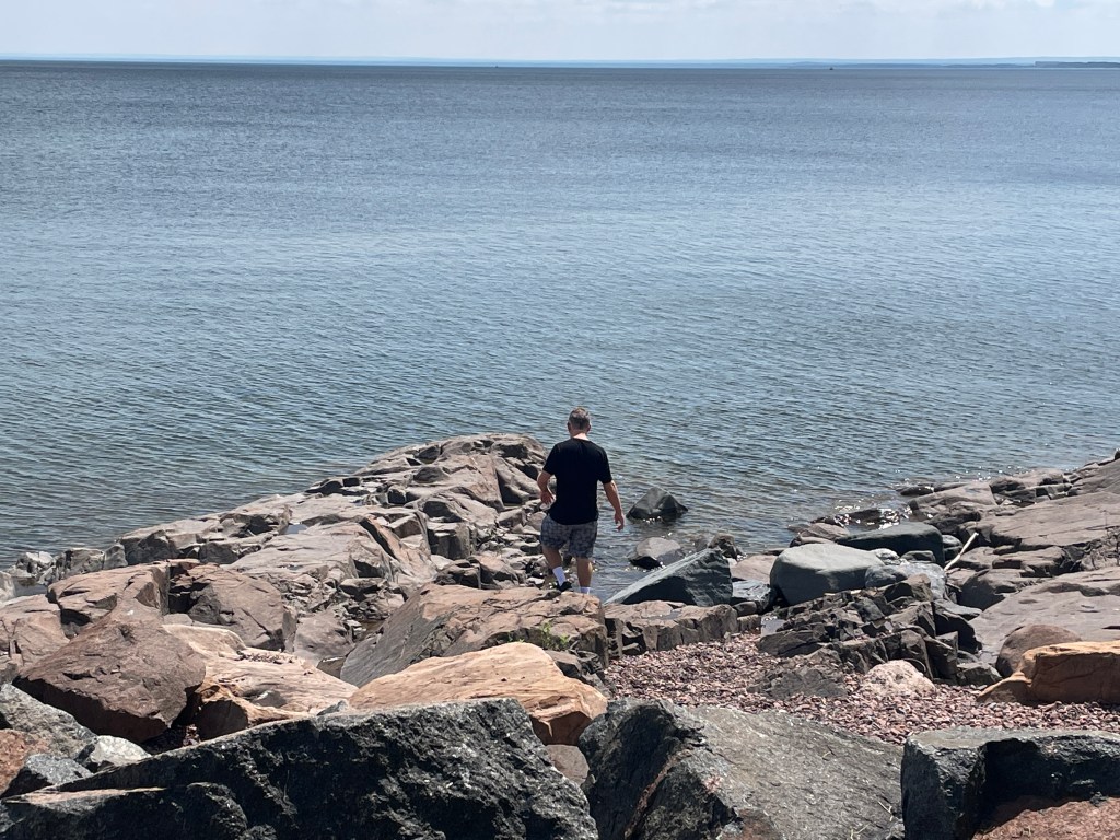 Adam climbing down rocks to touch the lake