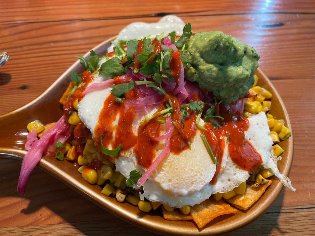 chilaquiles with chicken, roasted fresh corn, guacamole, red hot sauce and two poached eggs