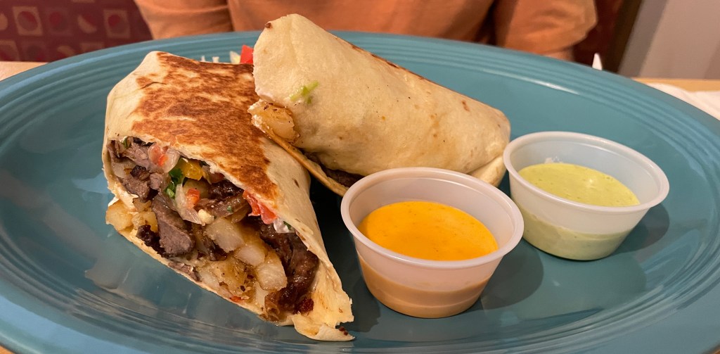 Burrito filled with steak, potatoes, and salsa. The burrito is grilled on the outside and comes with two different salsas.